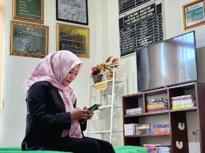 Salah satu warga Labuha, Aminah (45 tahun), sedang mencoba mempergunakan layanan LINDA dan LADUKU. Foto dokumentasi PN Labuha