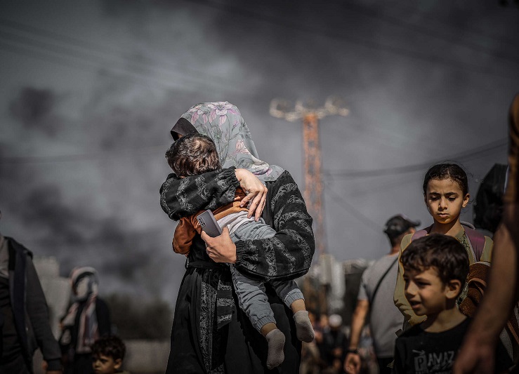 Seorang ibu di Gaza utara menutupi wajah anaknya untuk melindungi diri dari asap saat warga Palestina melarikan diri dari pemboman Israel di Jalur Gaza pada 10 November 2023. Foto: truthout-org/Belal Khaled/Anadolu melalui Getty Images