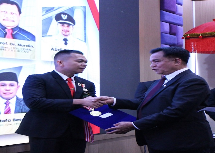 Menko Yusril Ihza Mahendra menyerahkan penghargaan kepada Hakim Fauzan Prasetya. Foto : Istimewa